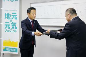 寄付金の目録を手渡す明治安田生命の古賀生治新潟支社長(左)=新潟市役所