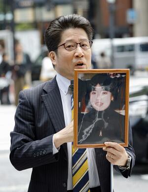 有本恵子さんの写真を手に署名活動する拉致被害者家族会代表の横田拓也さん=26日、東京・銀座