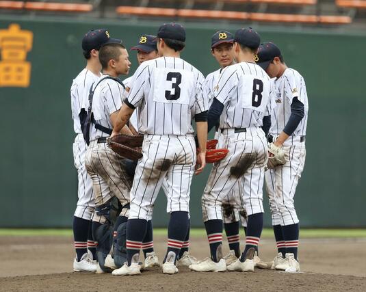 ７回のピンチでマウンドに集まる万代の選手たち＝７月１７日、三条市月岡４の三条パール金属スタジアム