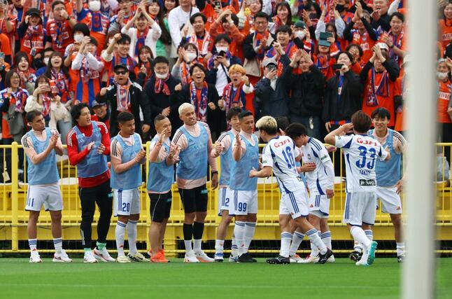 前半、FW小見洋太と喜ぶベンチ選手=三協フロンテア