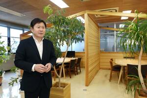県産木材で作った本社のシェアラウンジを紹介する小川和宣社長=新潟市西蒲区漆山