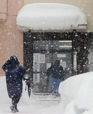雪が降りしきる中、投票に向かう市民＝８日、上越市