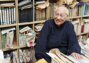 自宅書斎で資料を手にとる蒲原宏さん=2016年、新潟市中央区