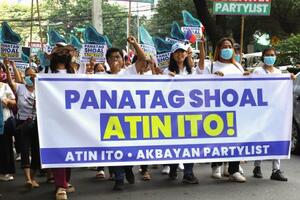 　マニラの中国大使館の関連施設前で、「スカボロー礁はわれわれのものだ」と書かれた横断幕を掲げ抗議する人たち＝２０２５年１０月（共同）