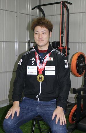 自宅のガレージで金メダルを胸に、W杯優勝の喜びを語る関川慎也さん=燕市杣木