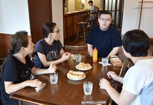 味噌バインミーを試食し、改良点などを話し合う柳醸造の関係者と川堀龍さん(中央)=長岡市殿町2