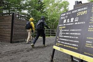 2024年6月、富士山の山開きを前に山梨県側から登山に向かう人たちヘ「弾丸登山」の注意を呼びかける看板