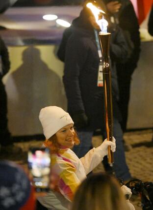 イタリア・コルティナダンペッツォの市街地で、聖火台へ向かう聖火ランナー＝６日（共同）