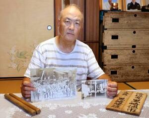 祖父の徳市さんが故郷の五島に送り焼失を逃れた写真や、戦前の「長崎くんち」で使われた看板を見せる黒崎雄三さん=9月、長崎市