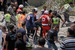 20日、レバノン南部でイスラエルによる空爆で破壊された建物の下から見つかった被害者を搬送する人たち(AP=共同)