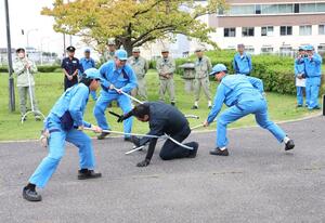 訓練で不審者役をさすまたで押さえつける東新潟火力発電所の所員ら=29日、聖籠町