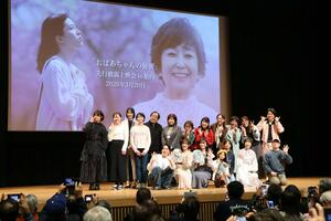 上映会後、舞台に上がったエキストラの地元出演者や主要キャストら＝胎内市新和町