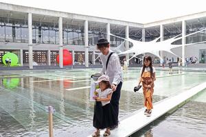 「阿弥陀渡り」と名付けられた水上通路を歩く来場者=7月13日、越後妻有里山現代美術館モネ