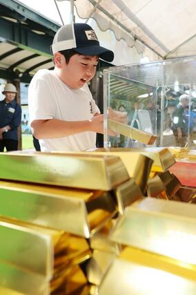 ７．５キロの金塊レプリカつかみ取りに挑戦する子どもたち。ずっしりとした重さに手こずっていた＝新潟市西区の新潟ふるさと村