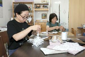 付け襟を作る高木涼子さん(左)と吉田節子さん。小さな商品でも縫う時間は約3時間かかるという=上越市東本町2