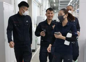 ベトナム人の同僚たちと談笑しながら職場の工場内を歩くトゥエンさん(左)=2025年11月、群馬県藤岡市