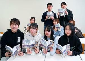 出版された「福島、語り継ぐ生活史」を手にする、福島第1原発事故の被災地を回り、住民らにインタビューを行った福島大の学生たち=3月、福島市