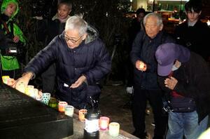 不戦を誓う集会で、献灯する参加者=8日午後、長崎市