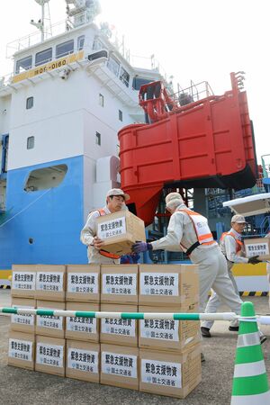 小木港周辺で行われた防災訓練で支援物資を運ぶ参加者ら=佐渡市小木町