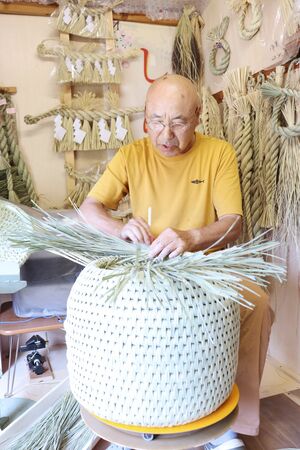 原材料から手作りにこだわった猫ちぐらを編む玄間隆さん=出雲崎町川西