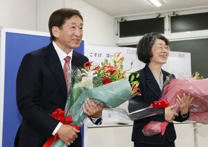 初当選を決め、花束を受け取った小菅淳一さん(左)=26日午後11時過ぎ、上越市藤巻