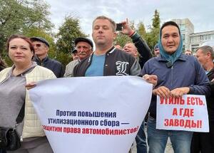 11日、ロシア極東ウラジオストクで開かれた廃物利用税引き上げに反対する集会で、メッセージを掲げる参加者(共同)