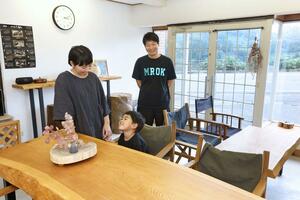 自宅を改装して設ける民泊施設のフリースペースで家族と談笑する松井幸治さん(写真中央)=長岡市山古志竹沢