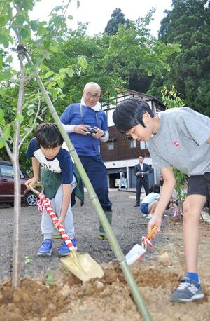 桜の苗木に土をかぶせる子どもたち=5月25日、新潟県南魚沼市上野の関興寺