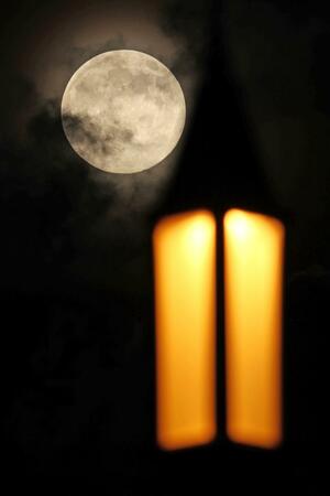 今年最も大きく見える満月「スーパームーン」。手前は萬代橋の街灯＝５日、新潟市中央区の萬代橋西詰