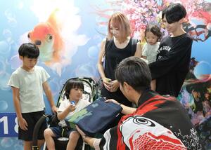 「錦鯉・金魚アクアリウム」の来場者5万人目となった家族=18日、新潟市中央区の朱鷺メッセ