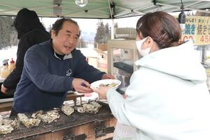 石川県穴水町から出店し、笑顔で能登産のカキを手渡す七海友也さん=2月24日、長岡市川口中山