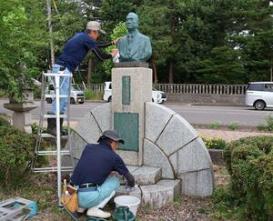 国友末蔵の胸像を磨く上越電友会の役員ら=上越市本城町