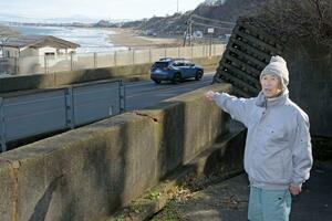 津波避難時の様子を振り返る佐内昭一さん。奥は津波が押し寄せたなおえつ海水浴場=上越市虫生岩戸
