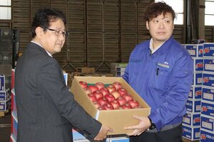 三条市の学校給食用として、佐藤伸治・市共同調理場長（左）に青森県産リンゴを寄贈する吉川睦夫・三条中央青果卸売市場果実部副部長＝三条市上須頃