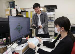 専用ソフトで作成したデザインを基に施した刺しゅうの仕上がりを確認する野口貴広社長(奥)=柏崎市茨目3