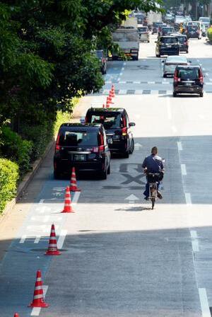 　車道の脇に設置された自転車専用レーン。自動車が停車していたため、自転車が車道側に大きくはみ出して走行していた＝１４日午後、東京都千代田区