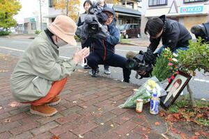 現場で遺影に手を合わせる被害者男性の妻=1日、新潟市東区