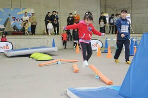 障害物レースで、回転する棒をジャンプでよける子ども=11日、佐渡市両津湊