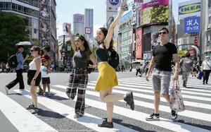 東京・渋谷駅前で、青信号でダッシュしてスクランブル交差点の中心に向かい、ポーズを決めて記念撮影する外国人=20日