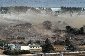 2011年3月11日、東日本大震災で押し寄せる津波にのみ込まれる住宅=宮城県名取市