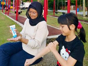 蚊よけ効果のある「ビオレガード モスブロックセラム」を使う親子=マレーシア(提供写真)