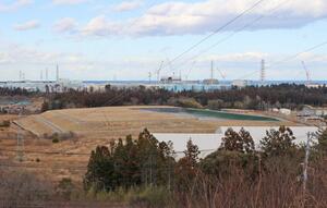 大熊町側にある除染土の貯蔵施設。貯蔵量は180万立方メートルで、奥に福島第1原発の建屋や処理水が入ったタンクが見えた=9日