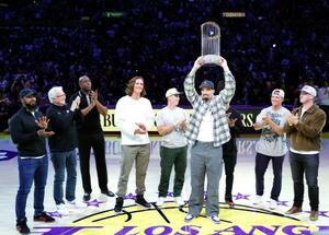 レーカーズ戦のコートに登場し、優勝トロフィーを掲げるドジャースのスネル=5日、ロサンゼルス(ゲッティ=共同)