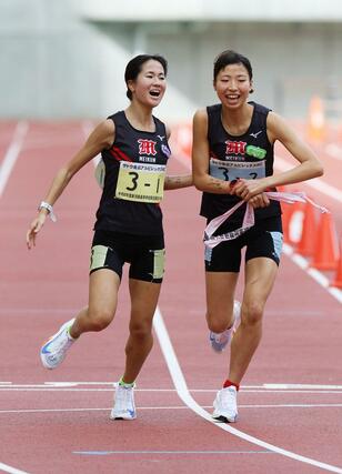 女子 新潟明訓の1区橋本和叶(左)が2区福田せりえにタスキリレー=新潟市中央区