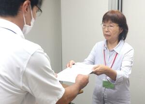 新潟県の最低賃金に関する異議申出書を提出する県労連の寺崎洋子議長=8月20日、新潟市中央区
