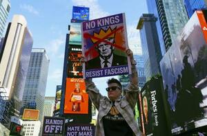 米ニューヨークの観光名所タイムズスクエアで、「王はいらない」と書かれたプラカードを掲げるデモ参加者=2025年10月(共同)