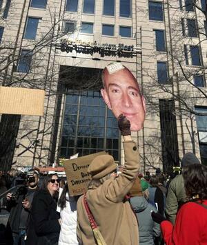 　米紙ワシントン・ポスト本社前で、ジェフ・ベゾス氏を「強欲」と批判し、大量解雇に抗議する女性＝５日、ワシントン（共同）