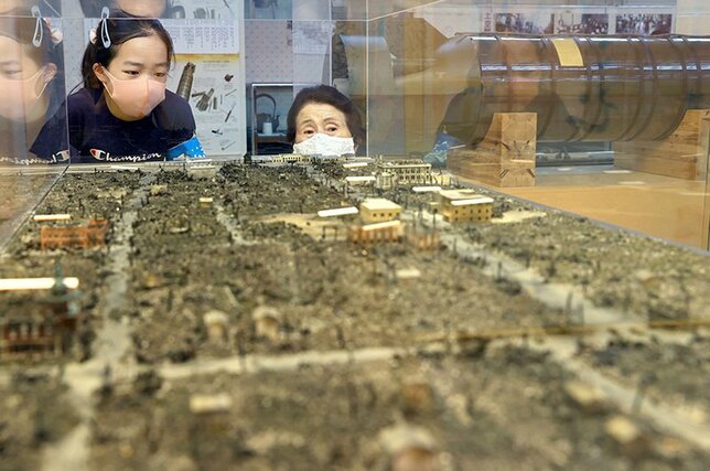 長岡空襲で焼け野原になった街の模型を見ながら、今泉恭子さん（右）の説明を聞く渋谷日向里さん＝長岡市の長岡戦災資料館