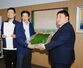 本町そ菜出荷組合のメンバーからもとまちきゅうりを受け取る佐野大輔市長（右）＝１３日、燕市役所