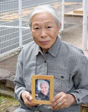 　母の津崎操さんの遺影を手に取材に応じる冨永真由美さん＝３月、熊本市